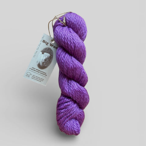 Purple skein of yarn with a label on a light gray background