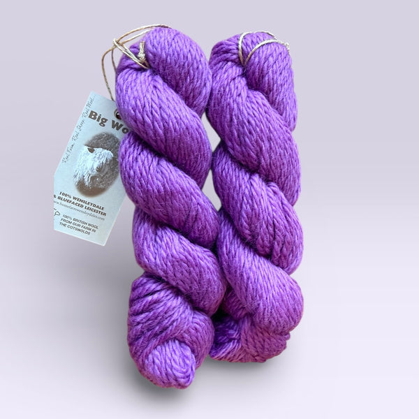 Two skeins of purple yarn with a label on a light purple background