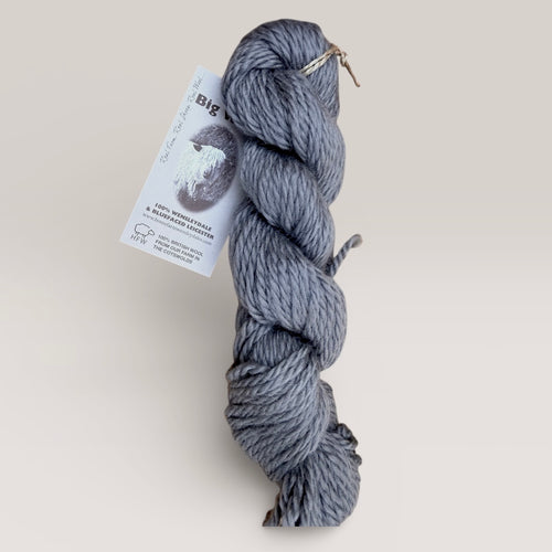 Gray skein of yarn with a home farm wool label on a light gray background