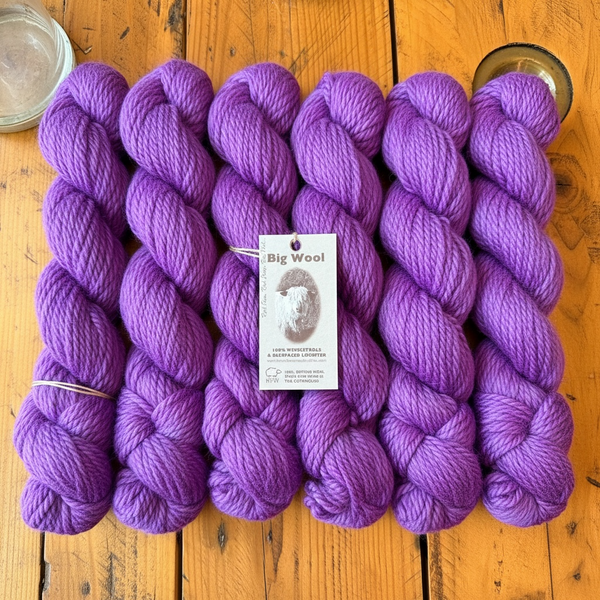 Purple yarn skeins with a 'Big Wool' label on a wooden surface