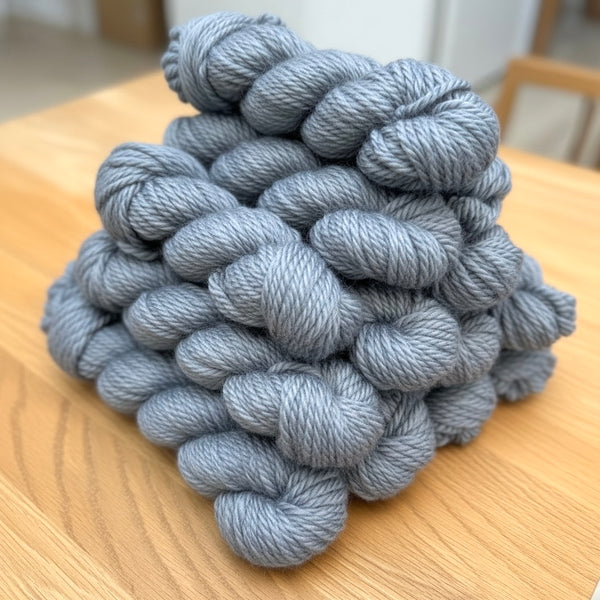 Gray skeins of yarn on a wooden surface