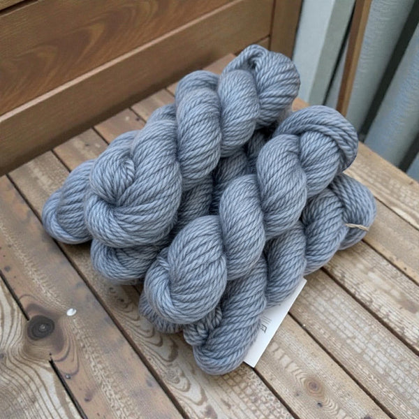grey  yarn skeins on a wooden surface